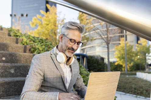 Businessman with eyeglasses working on laptop - JCCMF04420