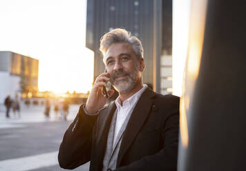 Nachdenklicher Geschäftsmann, der mit einem Smartphone telefoniert - JCCMF04426