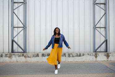 Smiling woman walking in front of wall - DMGF00629