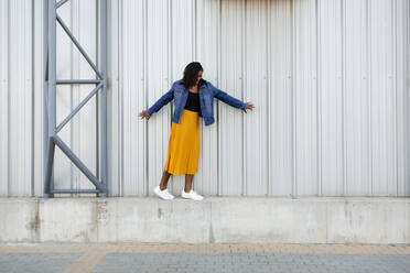 Young woman balancing self walking on wall - DMGF00633
