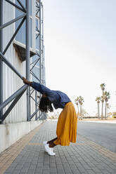 Woman bending holding metal on wall - DMGF00636