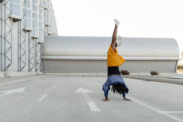 Woman practicing handstand on road - DMGF00640