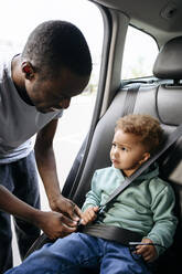 Vater stellt den Sicherheitsgurt seiner im Auto sitzenden Tochter ein - VYF00667