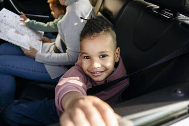Lächelnder Junge sitzt mit seiner Familie im Auto - VYF00674