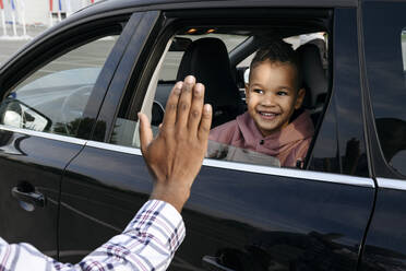 Vater gibt lächelndem Sohn im Auto ein High-Five - VYF00676