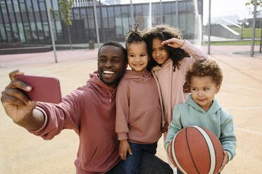 Vater macht Selfie mit Kindern über Handy auf dem Sportplatz - VYF00698