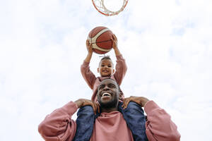 Fröhlicher Vater und Sohn spielen Basketball auf dem Sportplatz - VYF00706