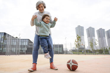 Großmutter hebt Enkelin auf Sportplatz - VYF00716