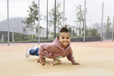 Lächelnder Junge spielt auf einem Skateboard auf einem Sportplatz - VYF00718