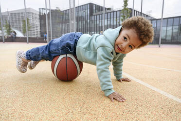 Cute girl balancing on basketball at sports field - VYF00719