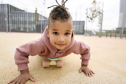 Junge auf dem Skateboard liegend auf einem Sportplatz - VYF00723