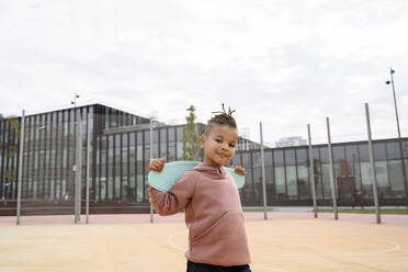 Boy carrying skateboard on shoulders at sports field - VYF00725