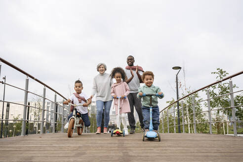 Kinder spielen mit Tretroller und Fahrrad auf der Brücke - VYF00733