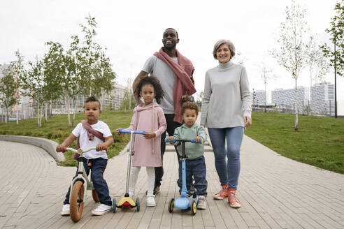 Smiling man standing with family at park - VYF00737