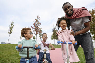 Glückliche Kinder mit Vater im Park stehend - VYF00739