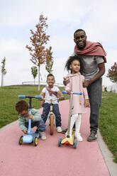 Vater steht mit Kindern auf dem Fußweg - VYF00740