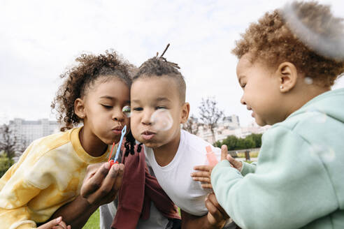 Happy children blowing bubble wand at park - VYF00752