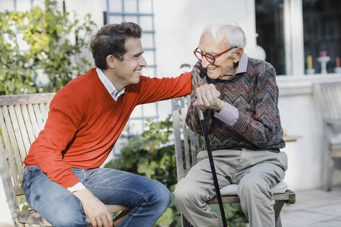 Happy man talking to elderly father in backyard - AANF00190