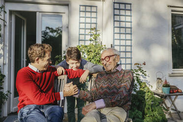 Smiling man holding hand of father by son in backyard - AANF00195