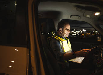 Ingenieur benutzt Laptop im Auto bei Nacht - UUF24981