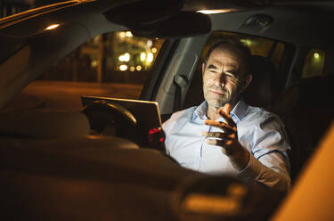 Businessman attending video call through laptop in car - UUF25002