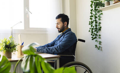 Disabled businessman working on laptop at home - JCCMF04430