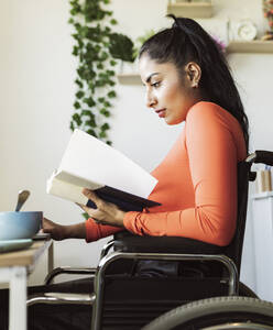 Junge behinderte Frau liest zu Hause ein Buch - JCCMF04447