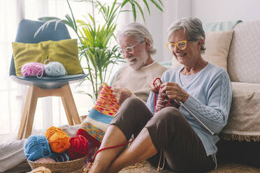 Senior couple knitting wool in living room - SIPF02652