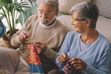 Couple knitting wool in living room - SIPF02653