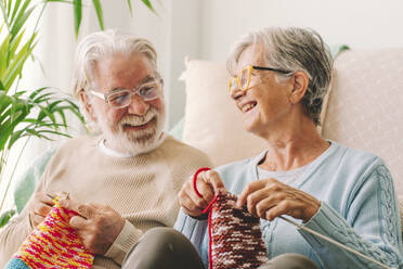 Smiling couple knitting wool with needle at home - SIPF02664