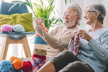 Senior man showing knitted wool to woman at home - SIPF02665