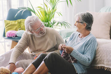 Senior couple with knitting needle sitting in living room - SIPF02668