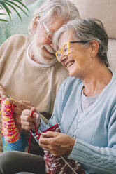 Happy senior couple with knitting needle in living room - SIPF02669