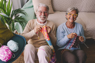 Smiling senior couple knitting wool at home - SIPF02685