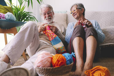 Senior couple with eyeglasses knitting wool at home - SIPF02688