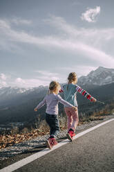 Playful girls walking with arms outstretched on road marking - OMIF00161