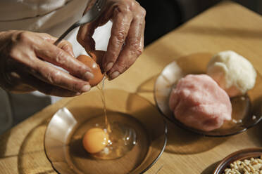 Woman breaking egg in bowl at kitchen - ACPF01393