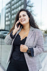 Lächelnde Geschäftsfrau, die mit einem Mobiltelefon spricht - DAMF00901
