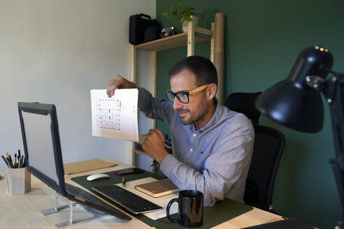 Smiling businessman showing business plan on video conference through laptop - VEGF05138