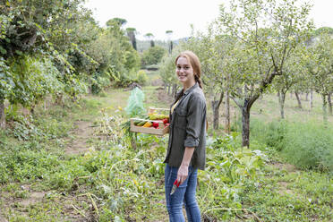 Smiling female farmer with vegetables in community garden - EIF02299