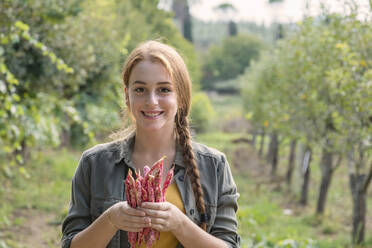 Lächelnde schöne Bäuerin mit frischen Bohnen im Garten - EIF02309