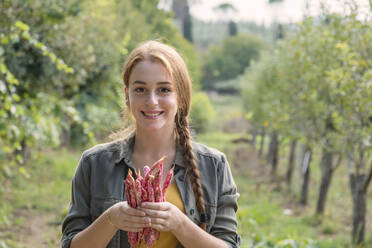 Smiling beautiful female farmer holding fresh beans in garden - EIF02309