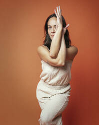 Flexible woman practicing yoga against orange background - JBYF00006