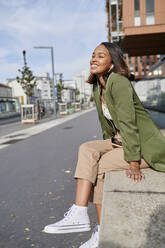 Smiling woman day dreaming on wall - KIJF04279