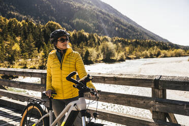 Woman with cycling helmet and bicycle on bridge - UUF25007