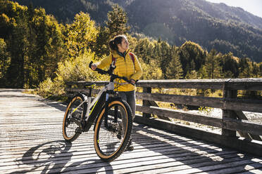 Lächelnde Frau, die auf einer Brücke Mountainbike fährt - UUF25018