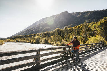 Mann schaut auf den Fluss und fährt Fahrrad an einem sonnigen Tag - UUF25027