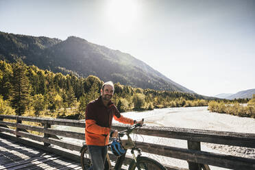 Lächelnder Mann, der auf einer Brücke Fahrrad fährt - UUF25028