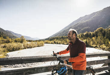 Man with bicycle walking on sunny day - UUF25029