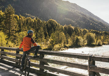 Mountainbiker mit Fahrrad an Brücke gelehnt - UUF25033